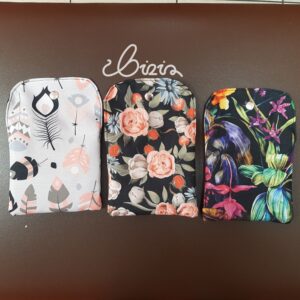 Etui na podpaski i tampony. Wykonane z materiału wodoodpornego. Wzór z piórami, różami i kwiatowy. Etui otwarte