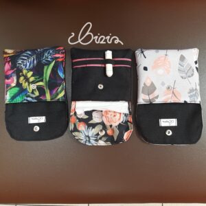 Etui na podpaski i tampony. Wykonane z materiału wodoodpornego. Wzór z piórami, różami i kwiatowy. Etui otwarte, wywrócone.