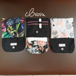 Etui na podpaski i tampony. Wykonane z materiału wodoodpornego. Wzór z piórami, różami i kwiatowy. Etui otwarte, wywrócone.