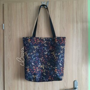 Torba na ramię we wzór jesiennych liści. Cała torba na tle drewna.